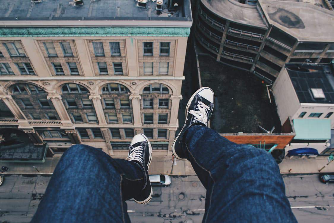 someone's legs dangling over the edge of a building